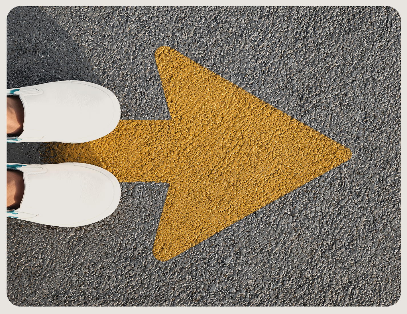 White sneakers on asphalt beside a golden yellow arrow pointing forward — a reminder that growth begins with one intentional step
