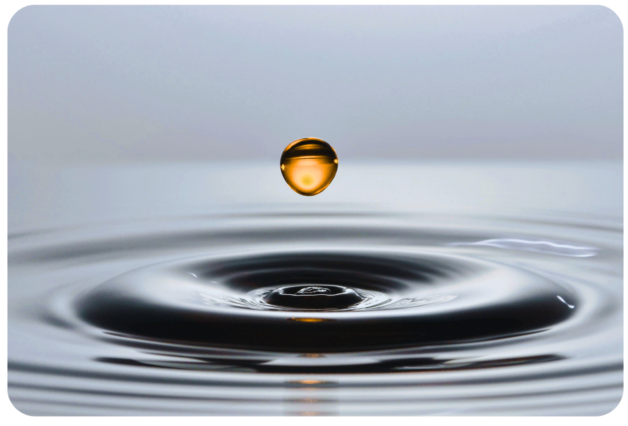 A golden water droplet falling toward a still surface, sending calm ripples outward — a visual metaphor for small changes creating lasting momentum.